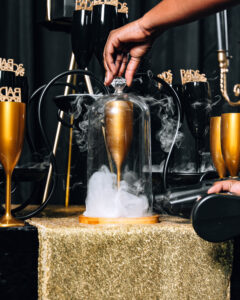Black and gold champagne cocktail display with dry ice smoke at luxury mobile bar event